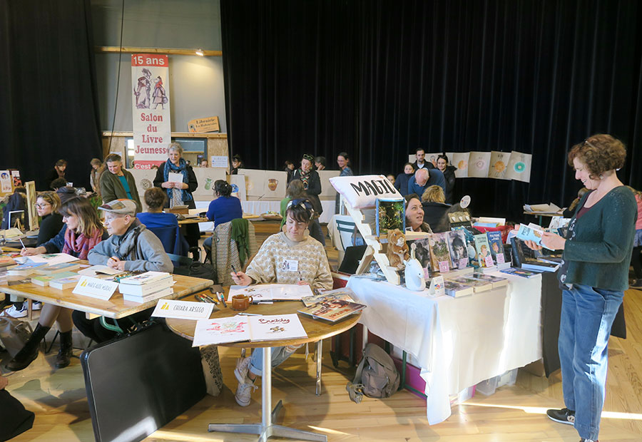 Photo des stands des autrices présentes au Salon du livre jeunesse, qui dédicacent leurs livres.