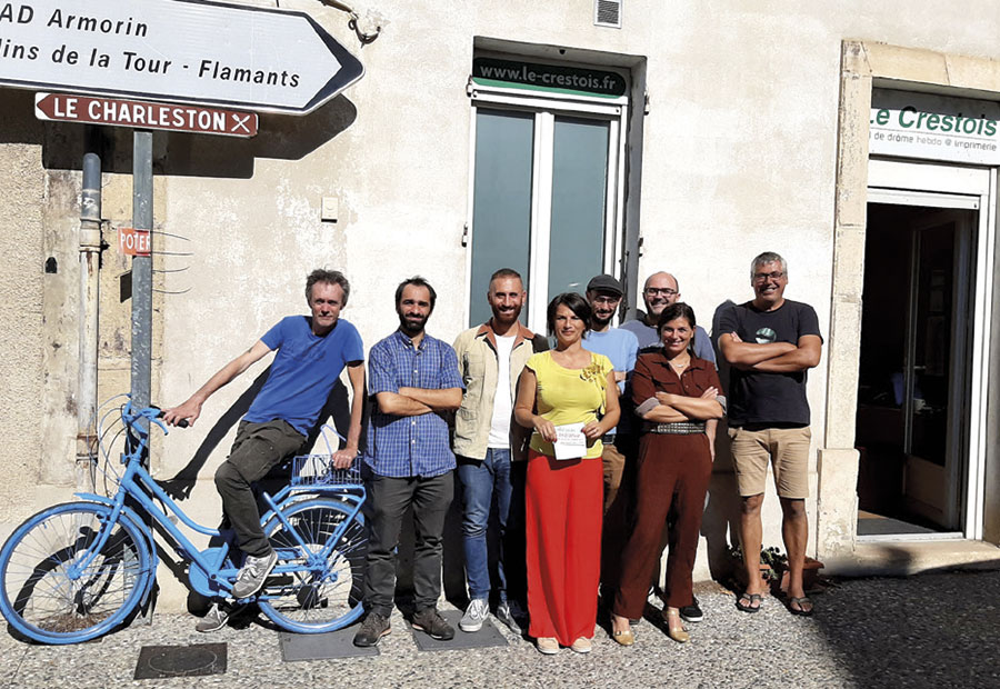 Photo de l'équipe du journal et du président du comité d'agrément de l'IVDD, devant les locaux de la rédaction. Apparaissent, de gauche à droite, Philippe Multeau sur un vélo peint en bleu, Martin Chouraqui, Aurélien Charle, Laure-Meriem Rouvier, Clément Chassot, Jean-Baptiste Bourde et Perrine Quenu à côté de Cyrille Fournier.