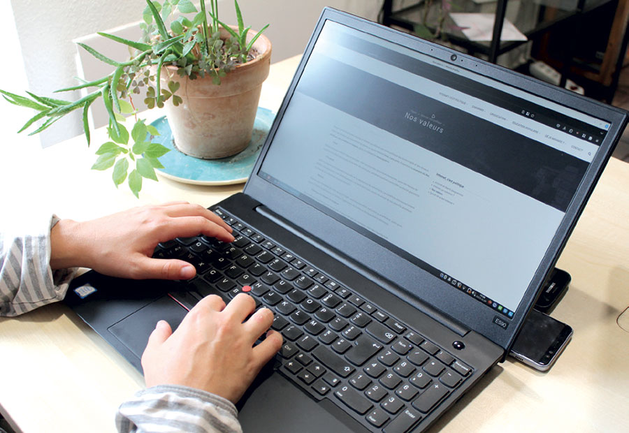 Photo de mains pianotant sur un ordinateur portable qui affiche la page "Nos valeurs" du site web de l'association Rézine.